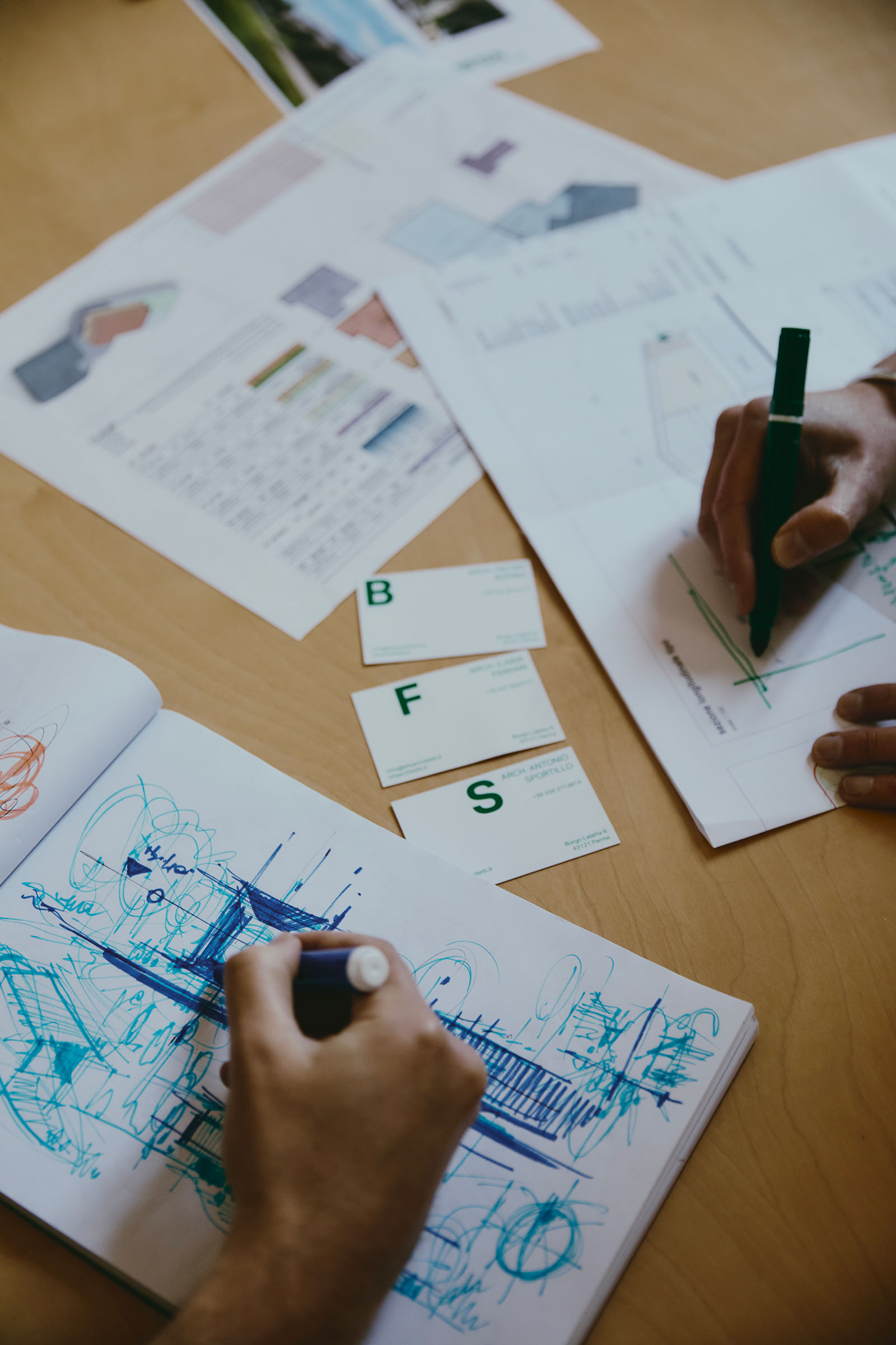dettaglio dei quaderni di lavoro e di mani che disegnano uno schizzo di un progetto architettonico